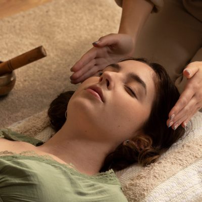 Reiki practitioner placing hands lightly on a relaxed person's back during a healing session.