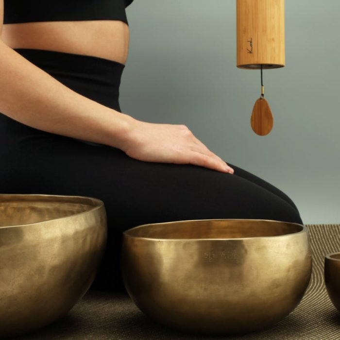 Sound healing session with singing bowls arranged on a mat, with incense burning nearby.